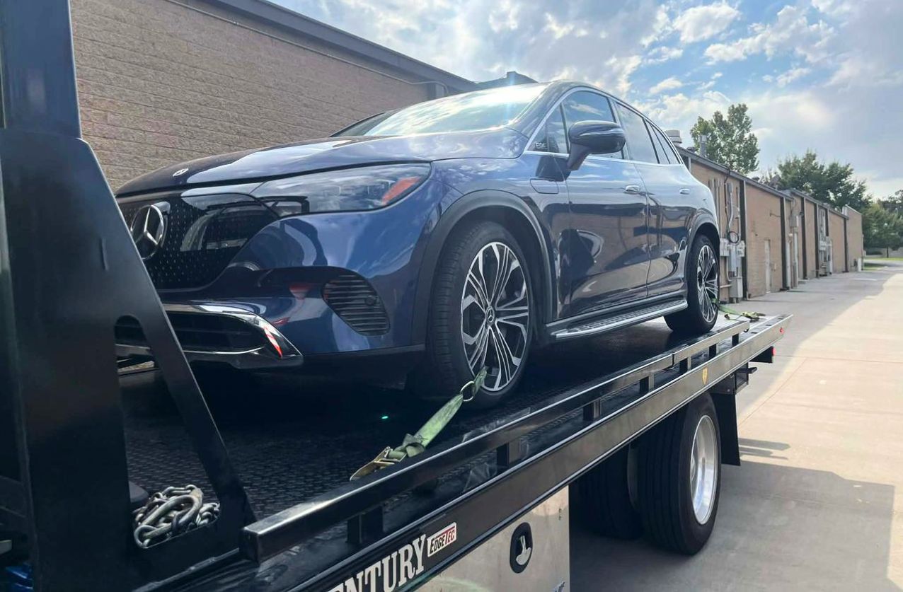 Tow truck service in Houston loading a sedan on a flatbed highway