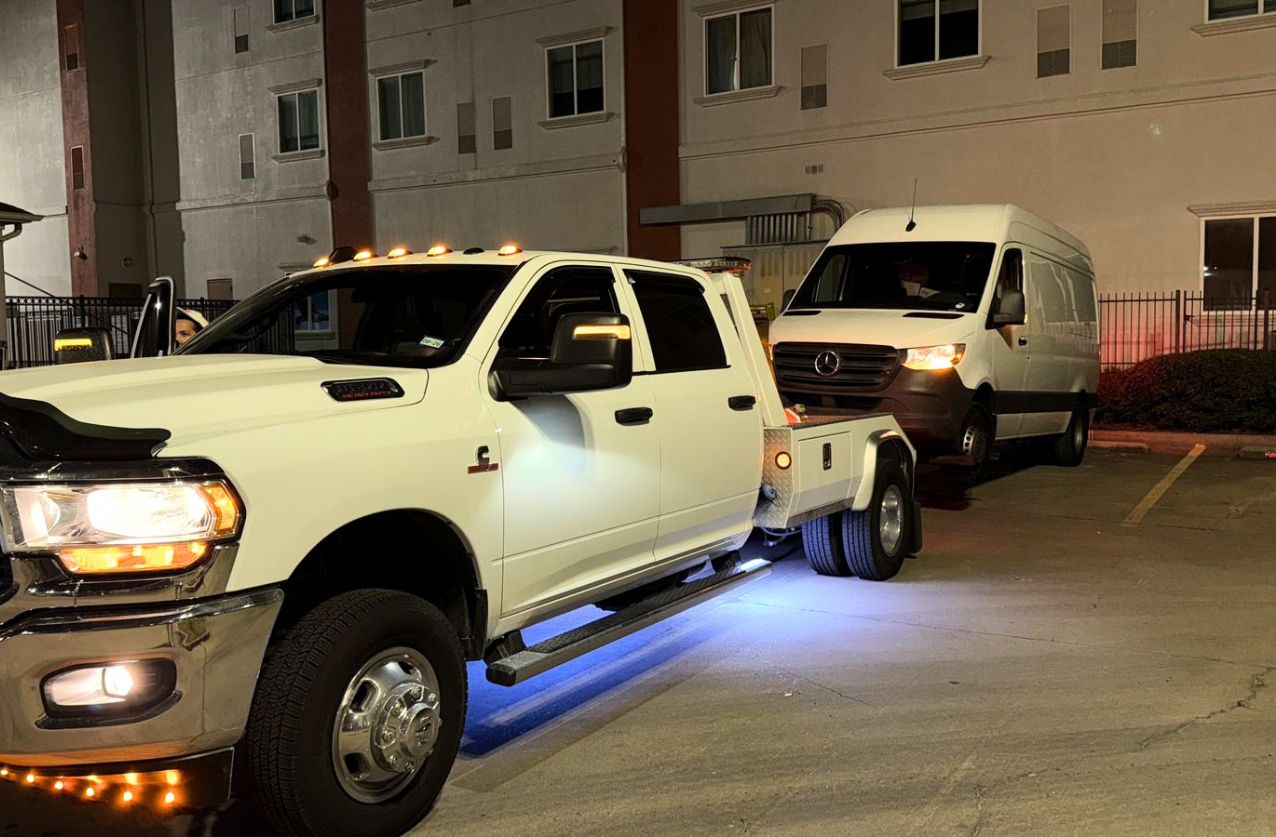 Tow truck service in Houston white truck towing van at night in apartment parking lot