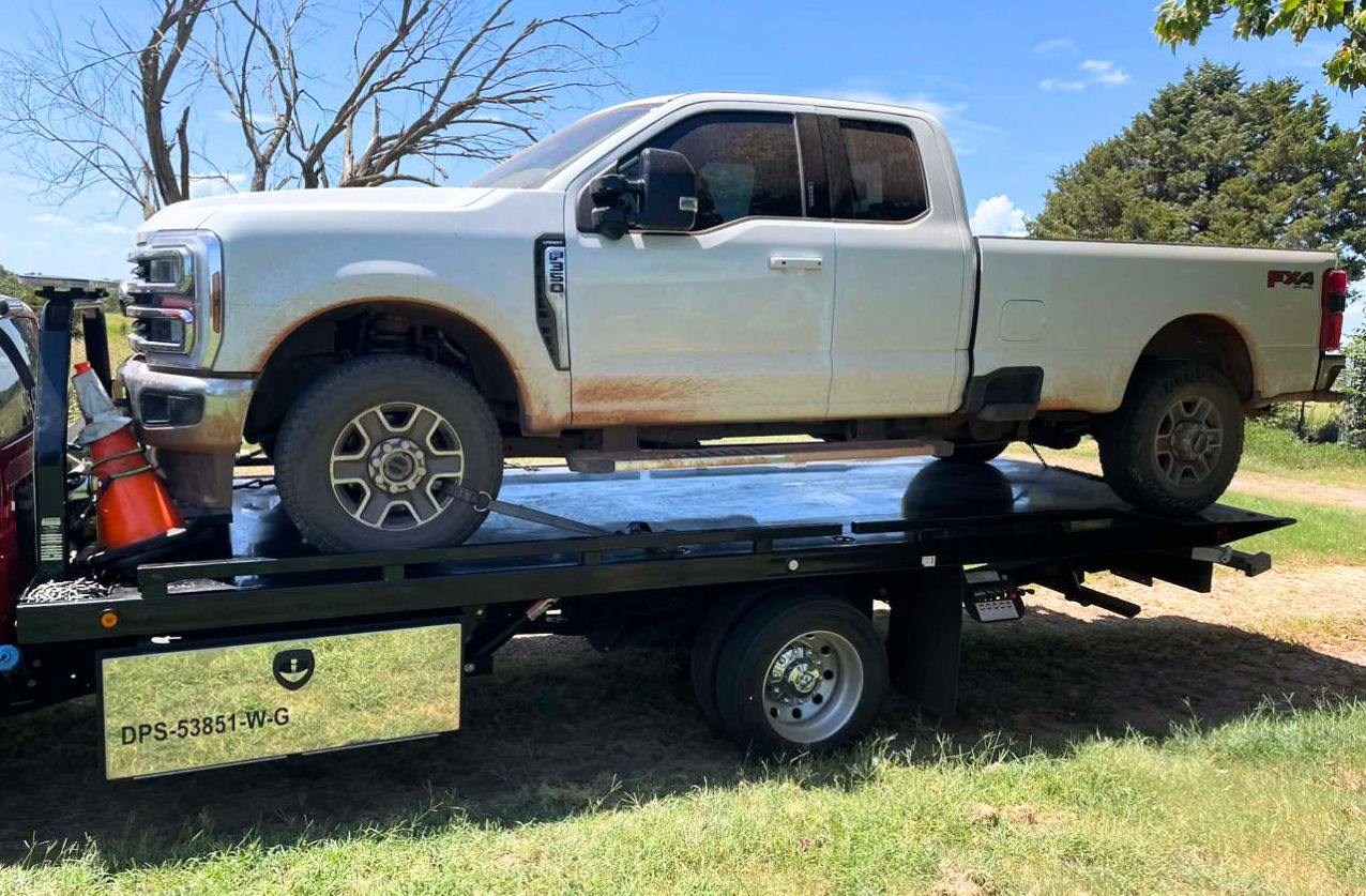 Heavy duty towing in Houston flatbed truck transporting a black pickup in a parking lot