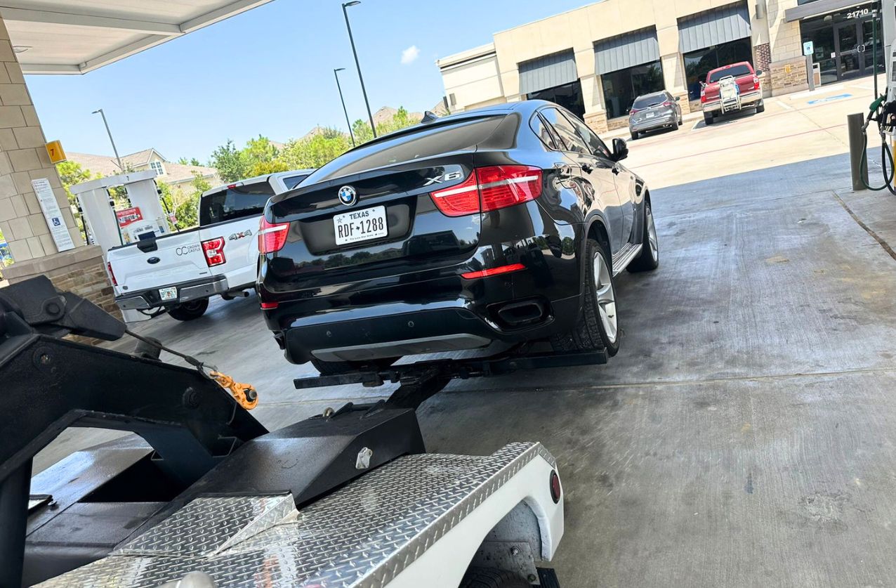 Tow truck service in Houston towing a black BMW from a gas station