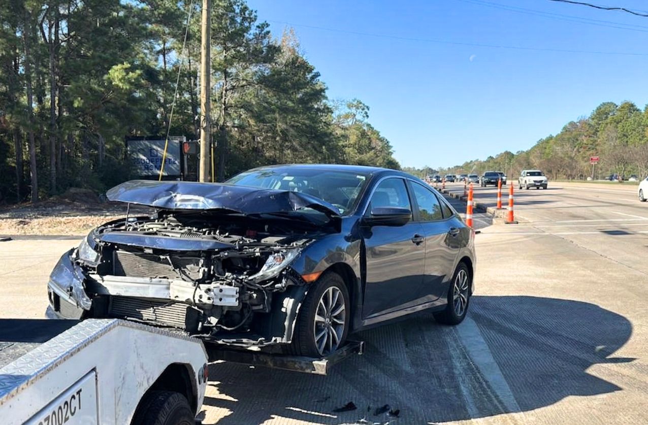 Wrecker services in Houston recovering a damaged black car on a busy road